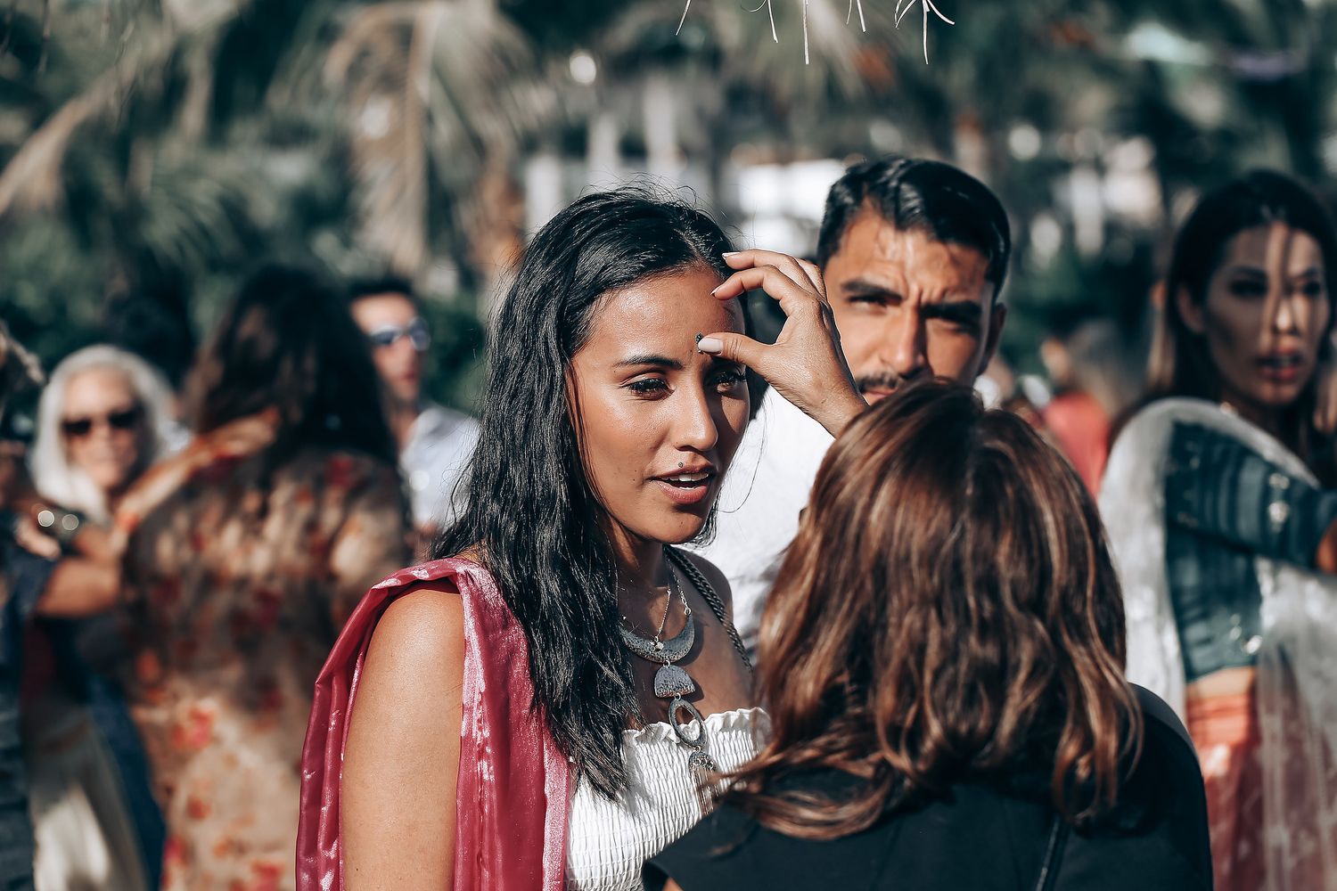 A crowd of wedding guests gathers outdoors during a celebration.