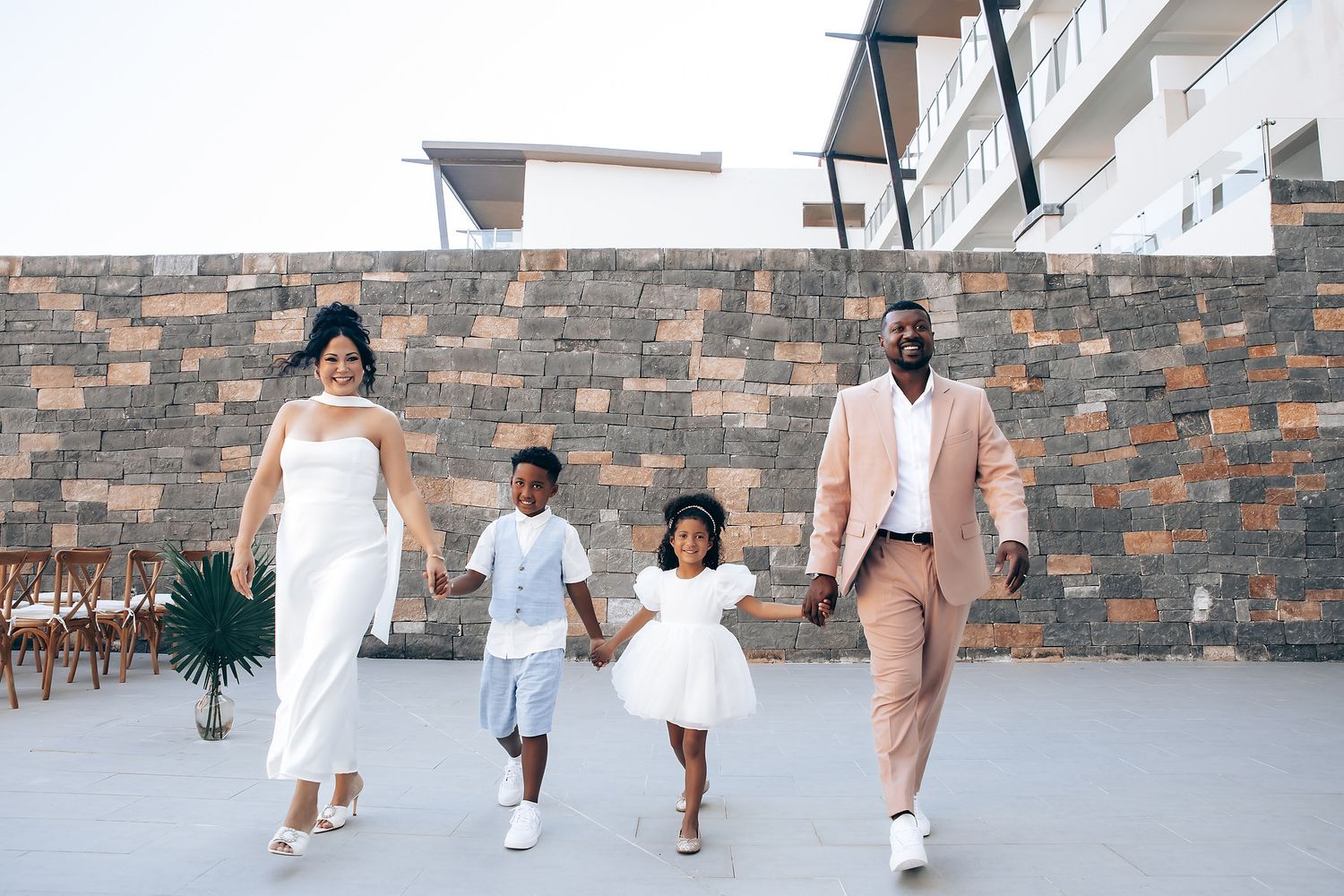 A family of four walks together in coordinated outfits with two small children in the middle.