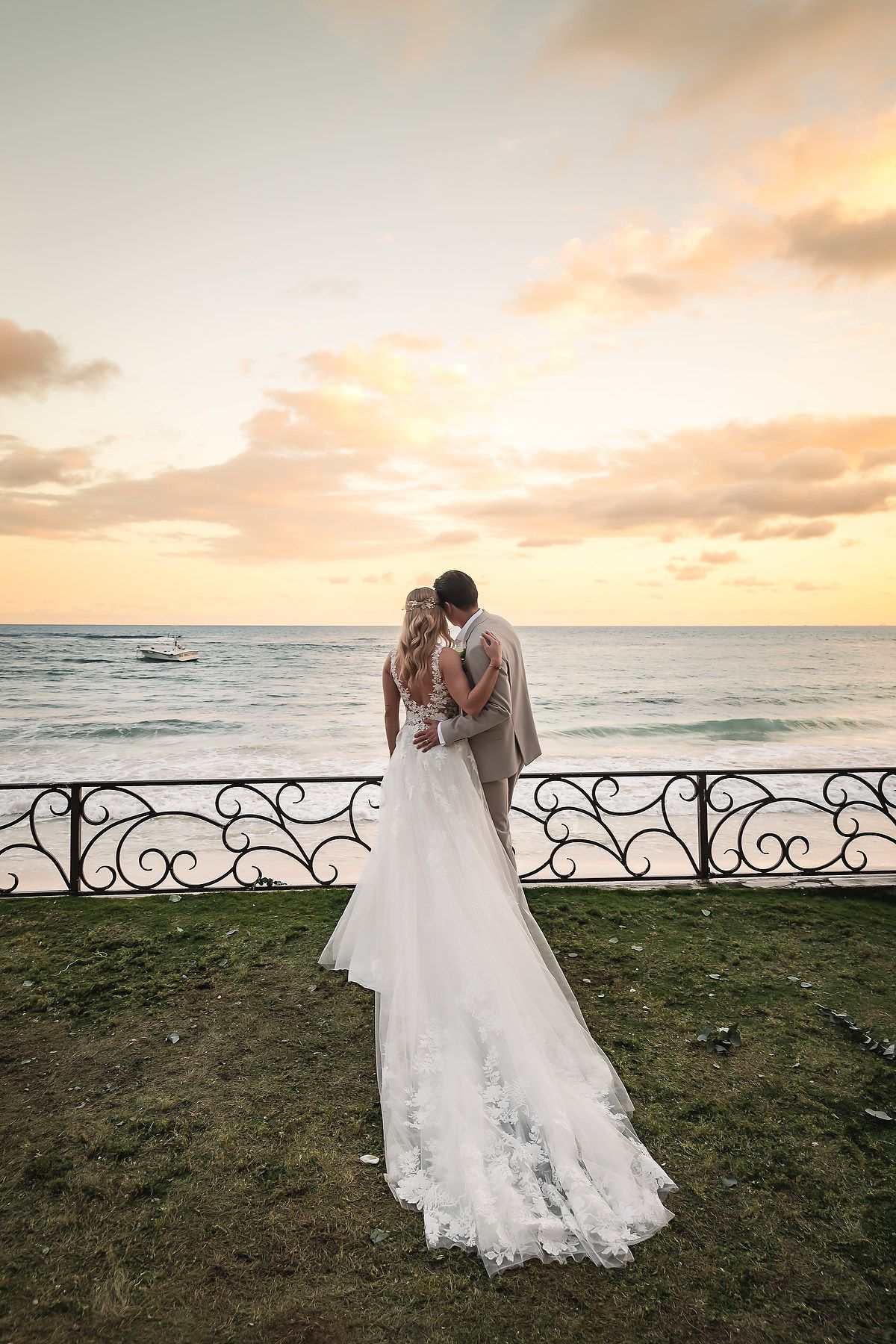Oceanfront sunset wedding portraits with ornate iron railing and dramatic sky.