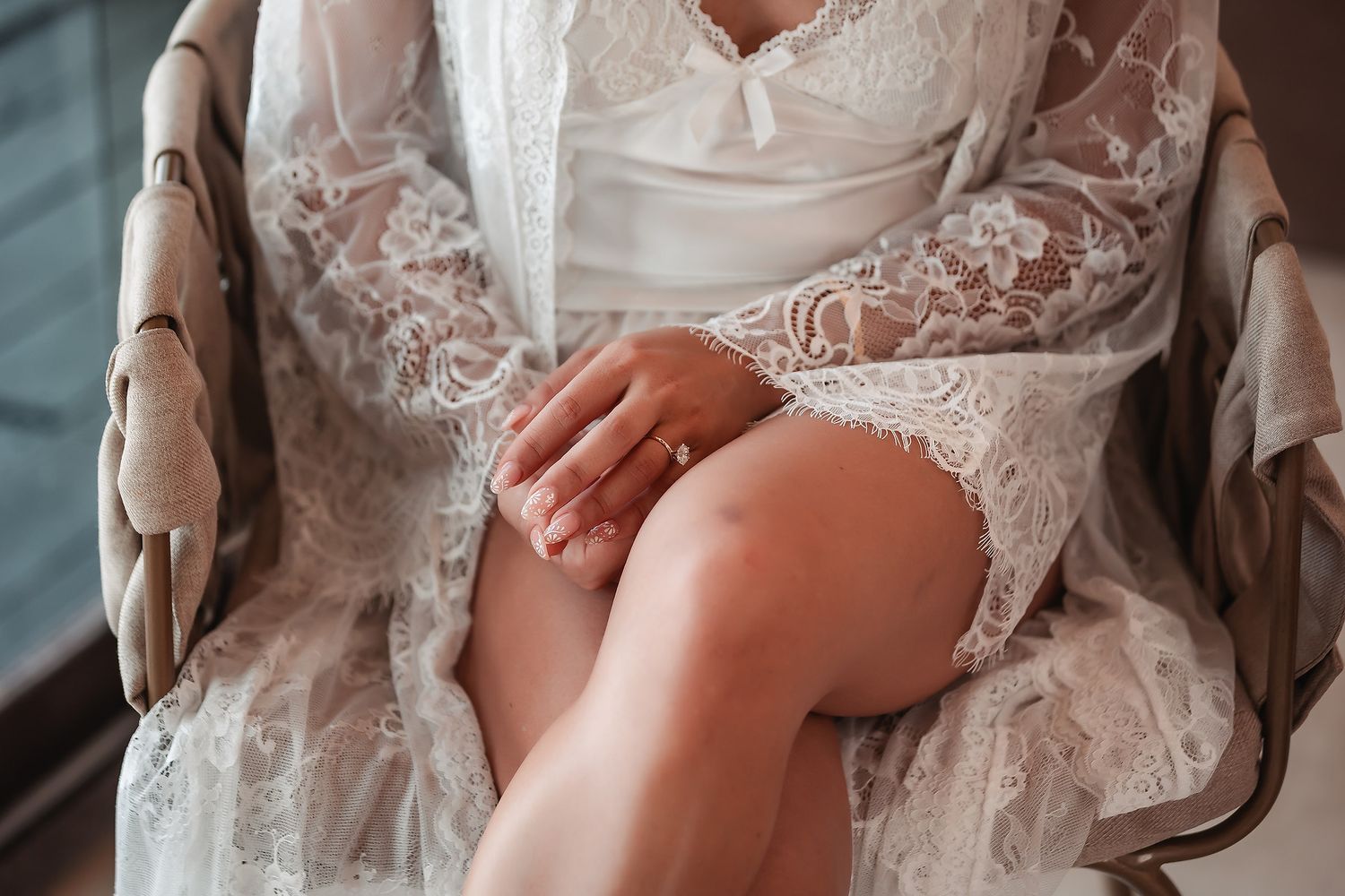 Elegant lace details of a white bridal robe captured in soft natural lighting.