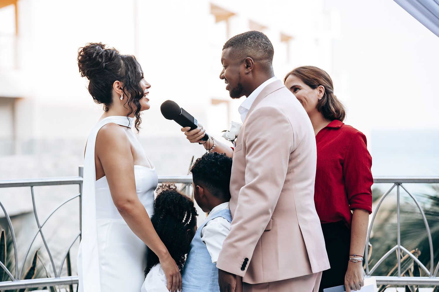 Wedding party gathered on outdoor terrace in elegant attire.