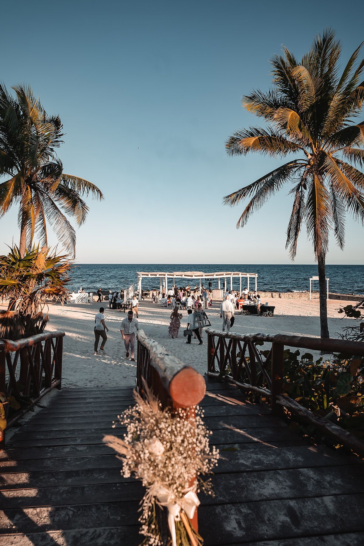 Palm trees line a beachfront walkway decorated with wedding flowers and decor.