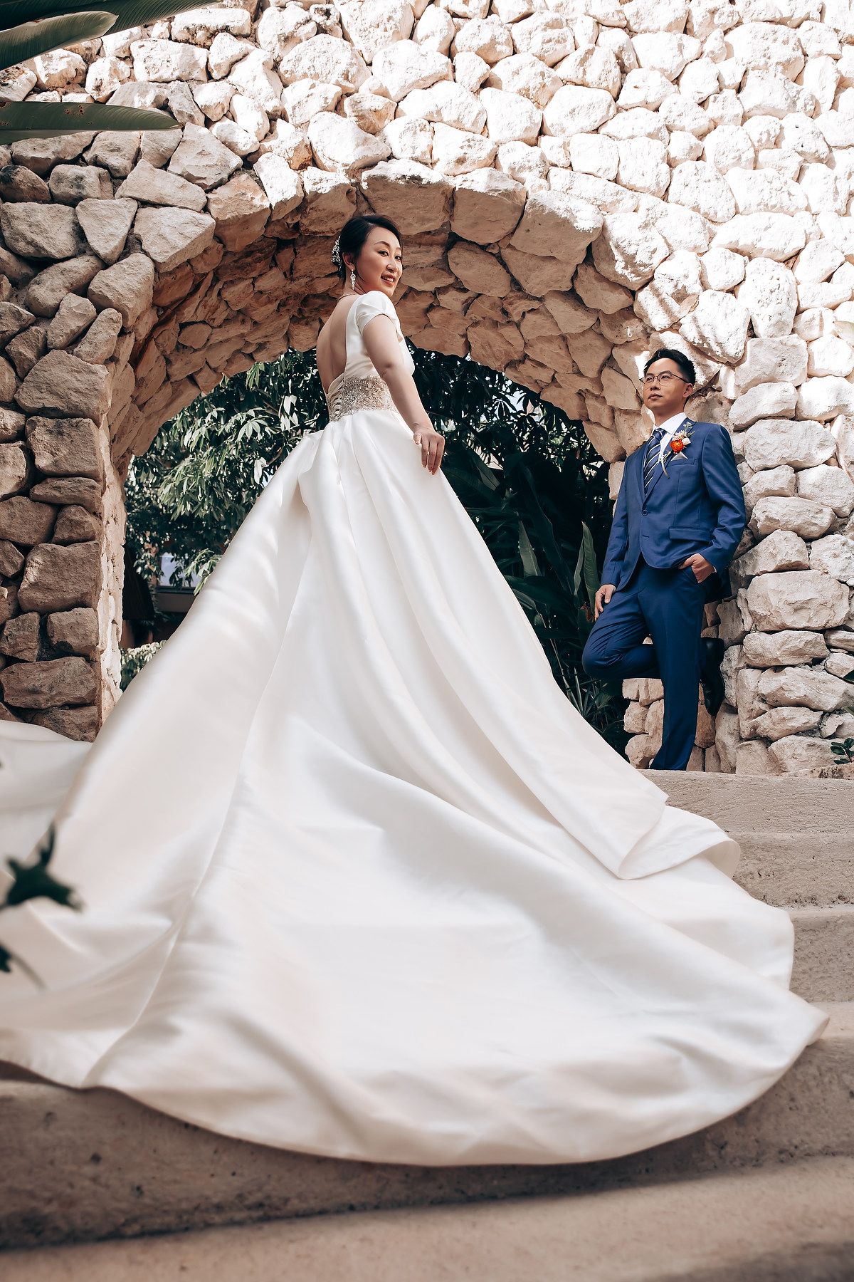 A flowing white wedding dress train sweeps across stone pavement in an artistic sequence of movement shots.