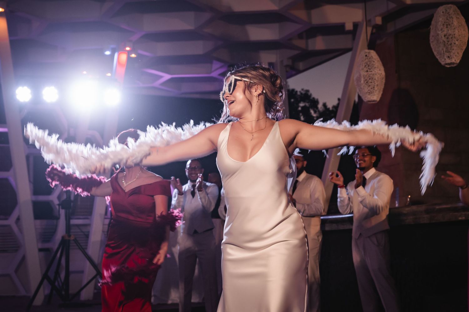 Wedding reception dance floor filled with celebrating guests under decorative lighting.