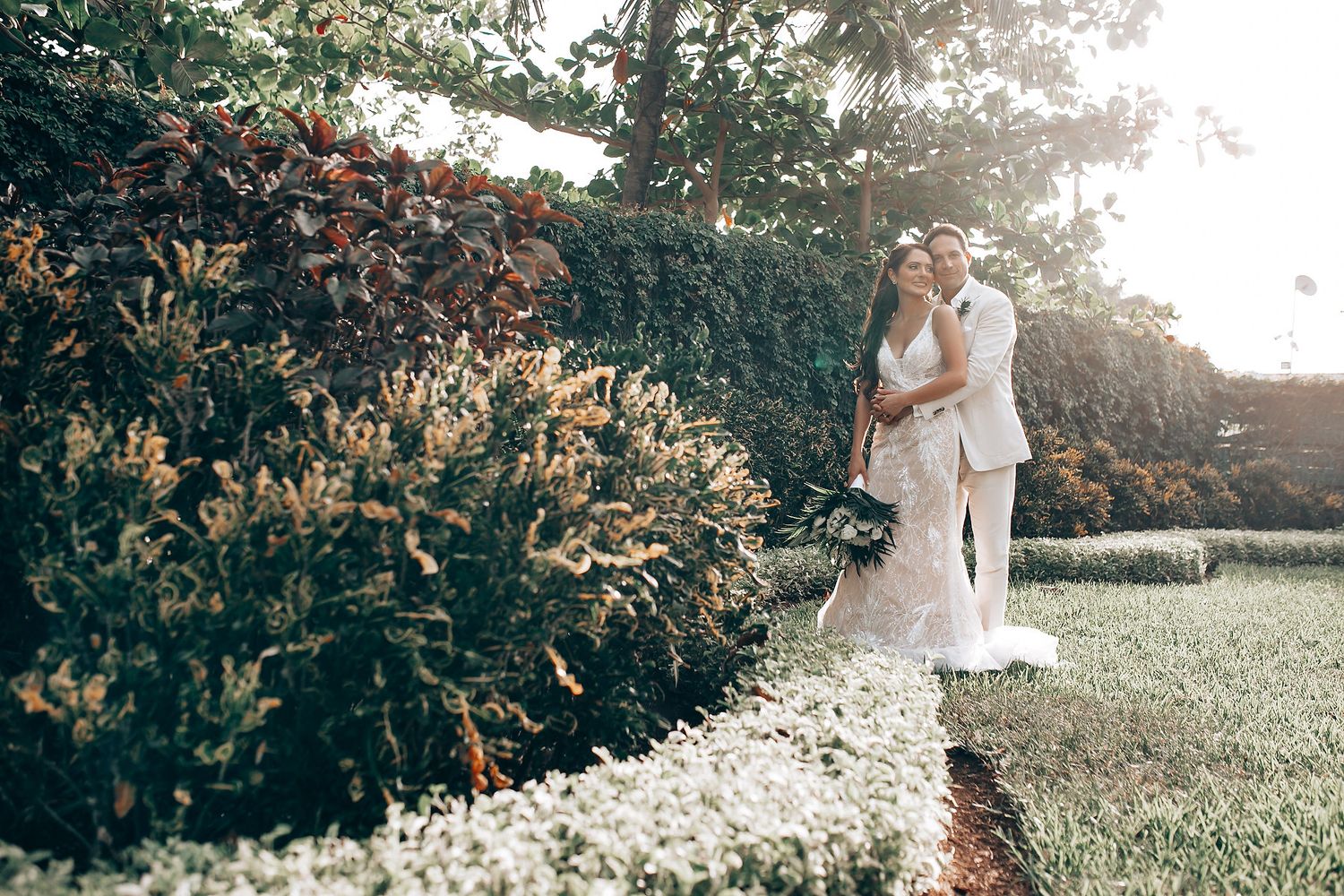 Romantic wedding photography in a sunlit garden with white flowers.