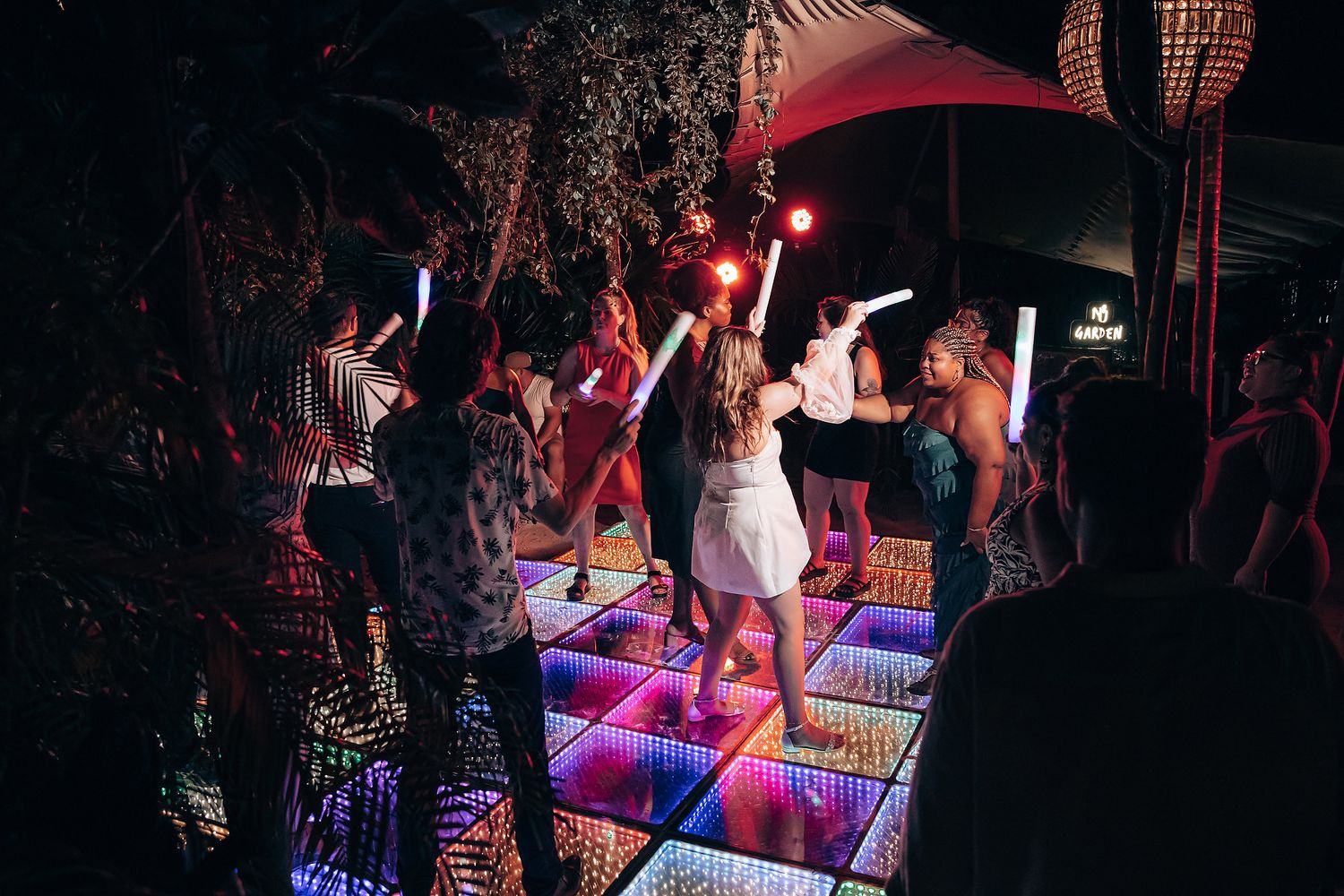 Dancers moving on a glowing LED dance floor during a nighttime celebration.