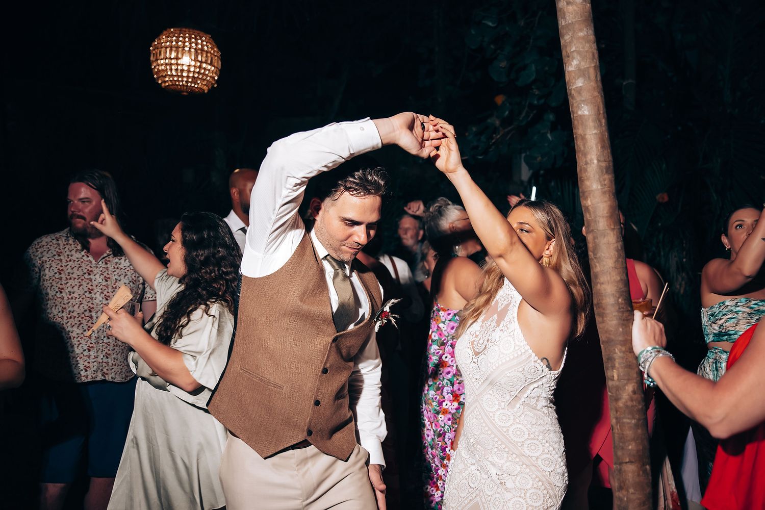 Guests enjoying a lively dance party under twinkling lights at an outdoor wedding celebration.