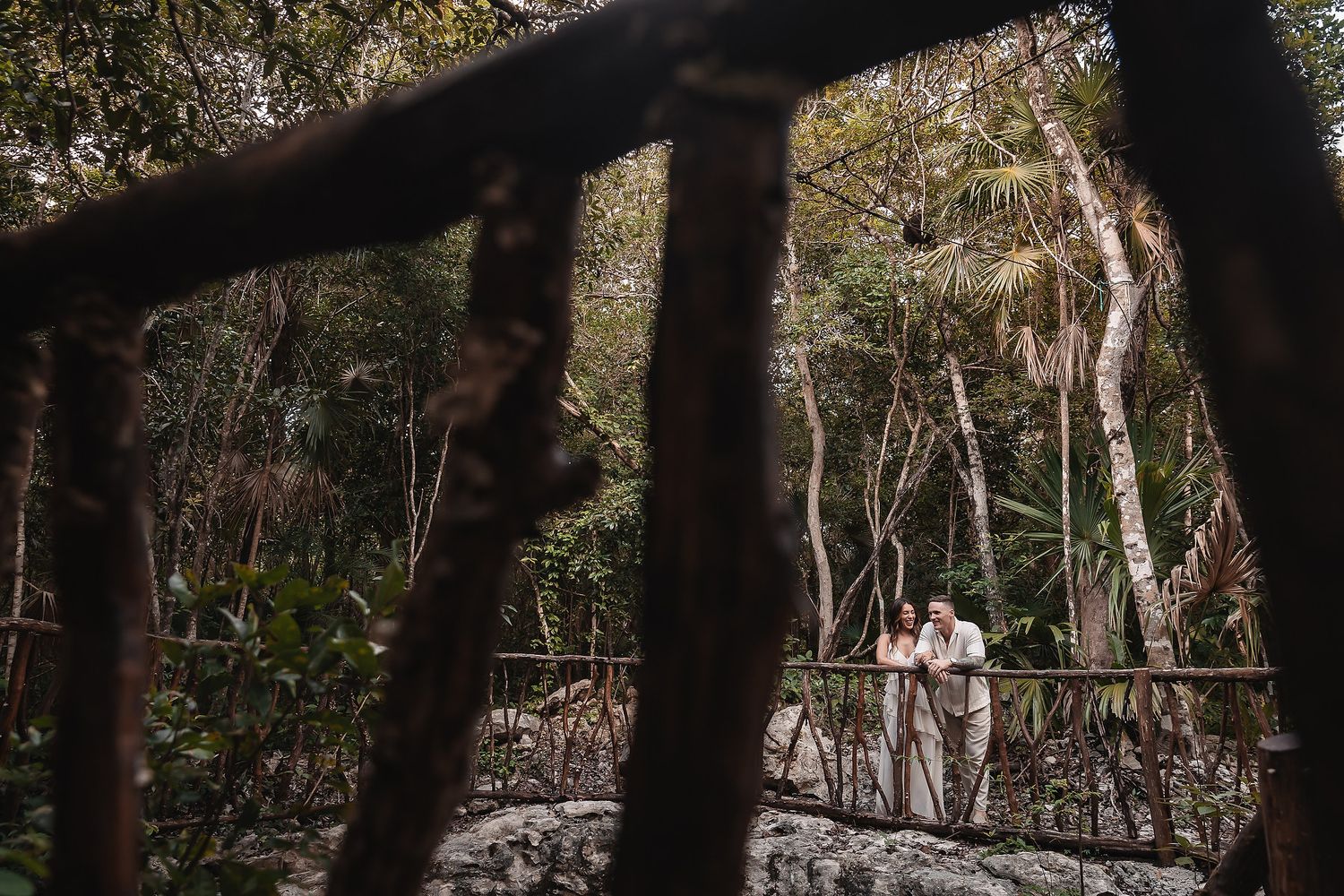 Two figures walk through a forest clearing framed by dark tree silhouettes.