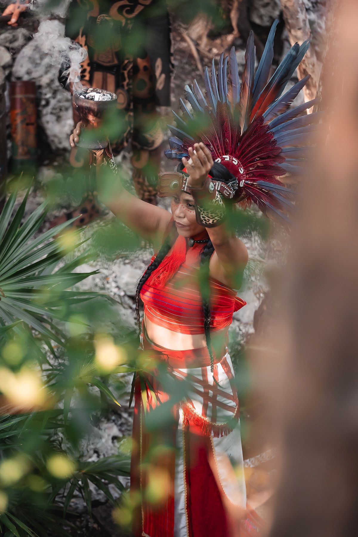 Vibrant red and feathered ceremonial decorations against a blurred natural background.
