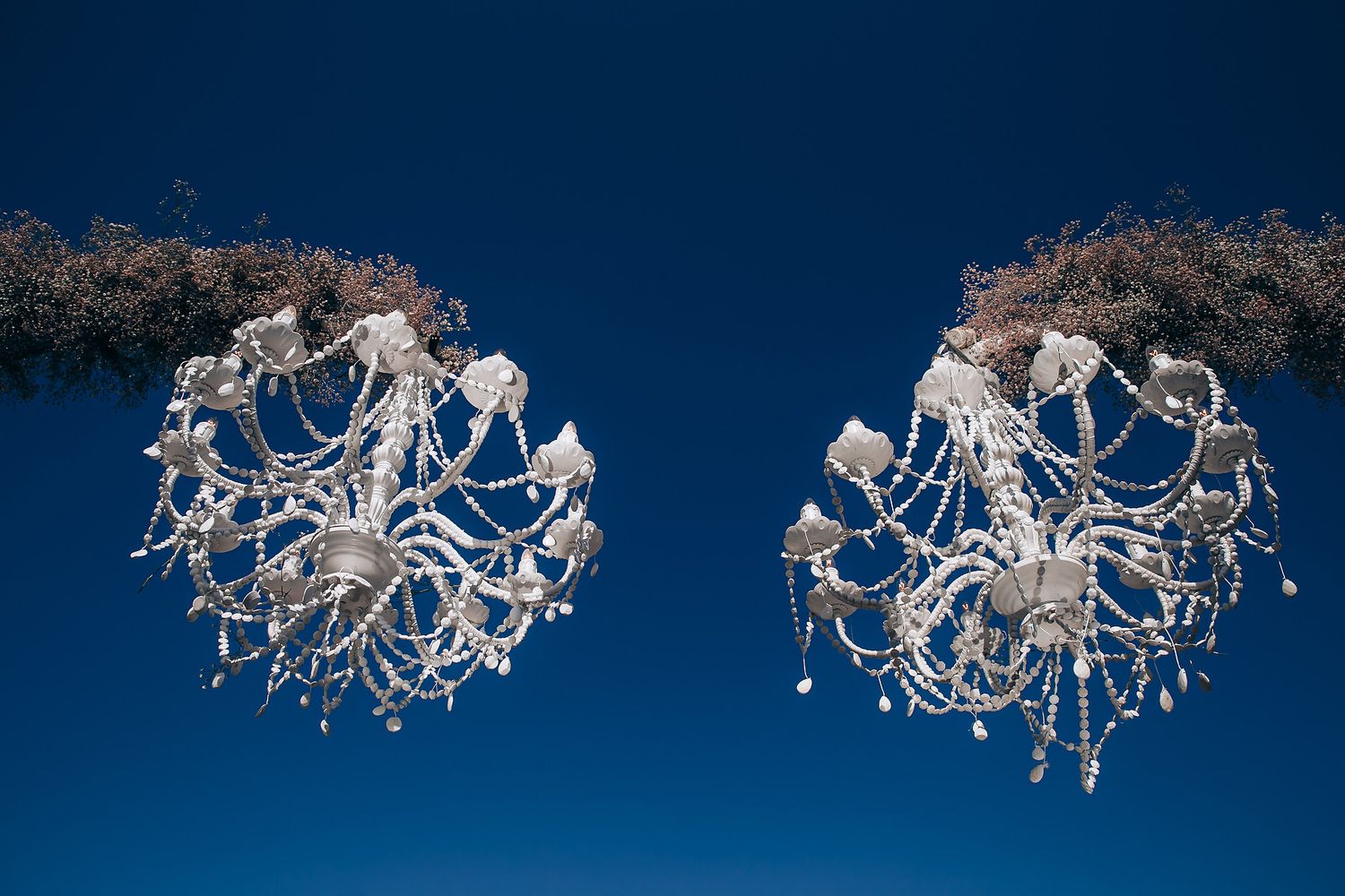 Elegant white crystal chandelier photographed in sequence showing rotation against dark blue background.