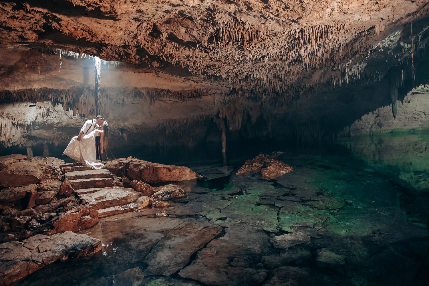 Natural sunlight streams into a majestic cave cenote creating a magical atmosphere for a sacred ceremony.