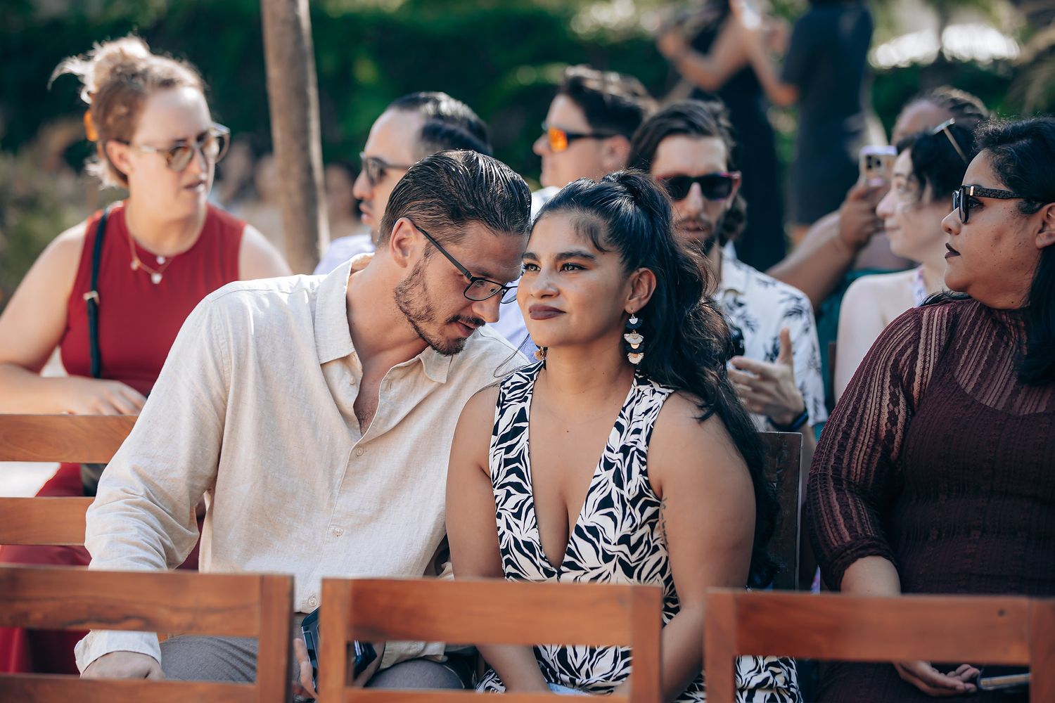 A group of people enjoying drinks and conversation at an outdoor restaurant patio on a sunny day.