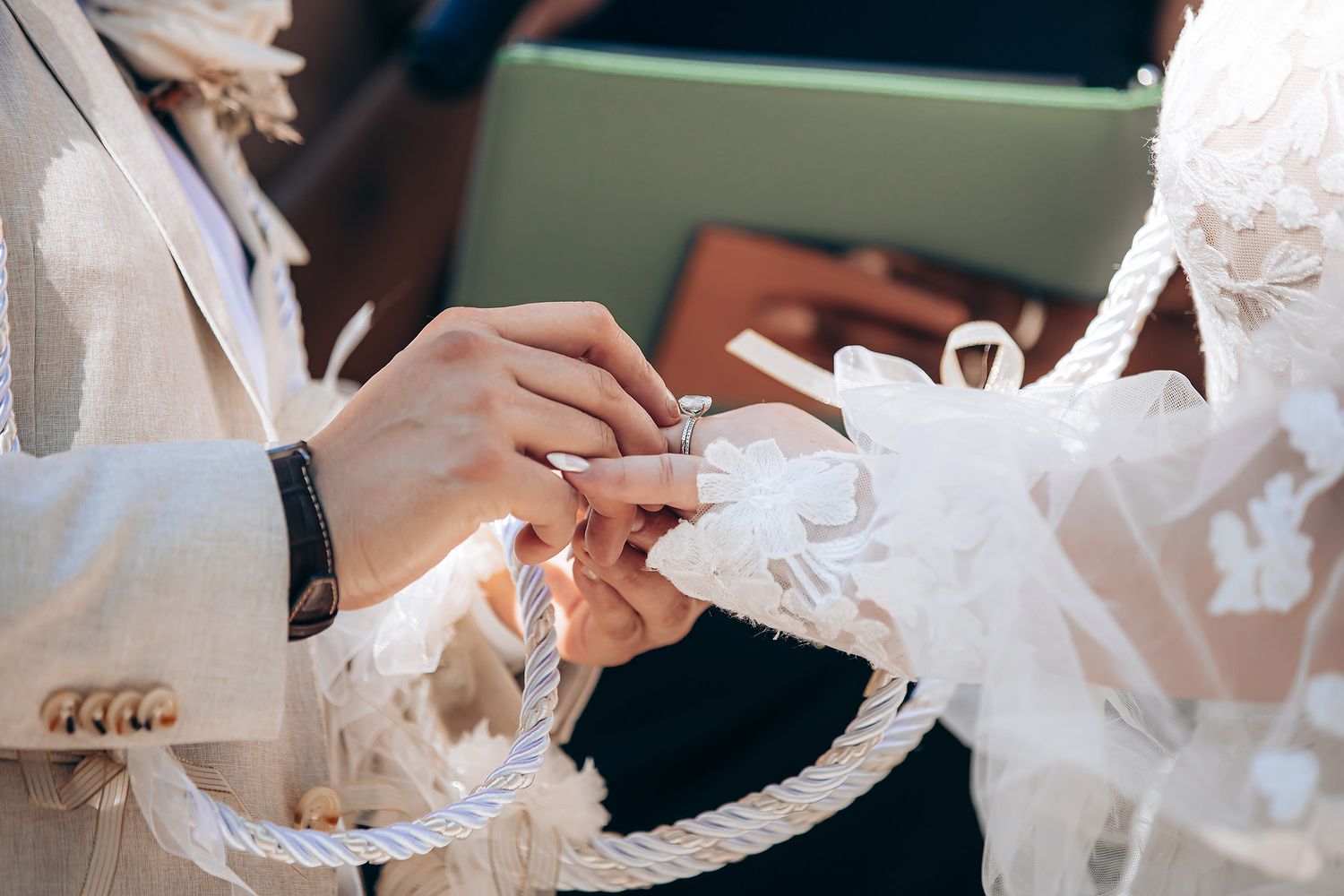 Close-up view of someone signing a wedding guestbook with an elegant pen at an ornate table.
