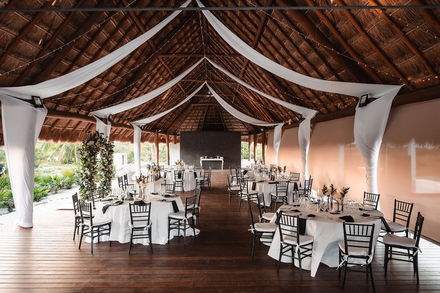 Elegant wedding reception venue with exposed wooden beams and white draping across the ceiling.