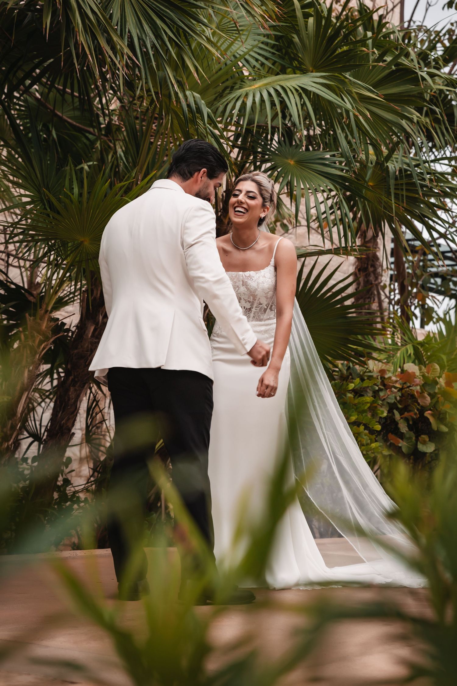 Romantic wedding couple dancing and embracing in a tropical garden setting.