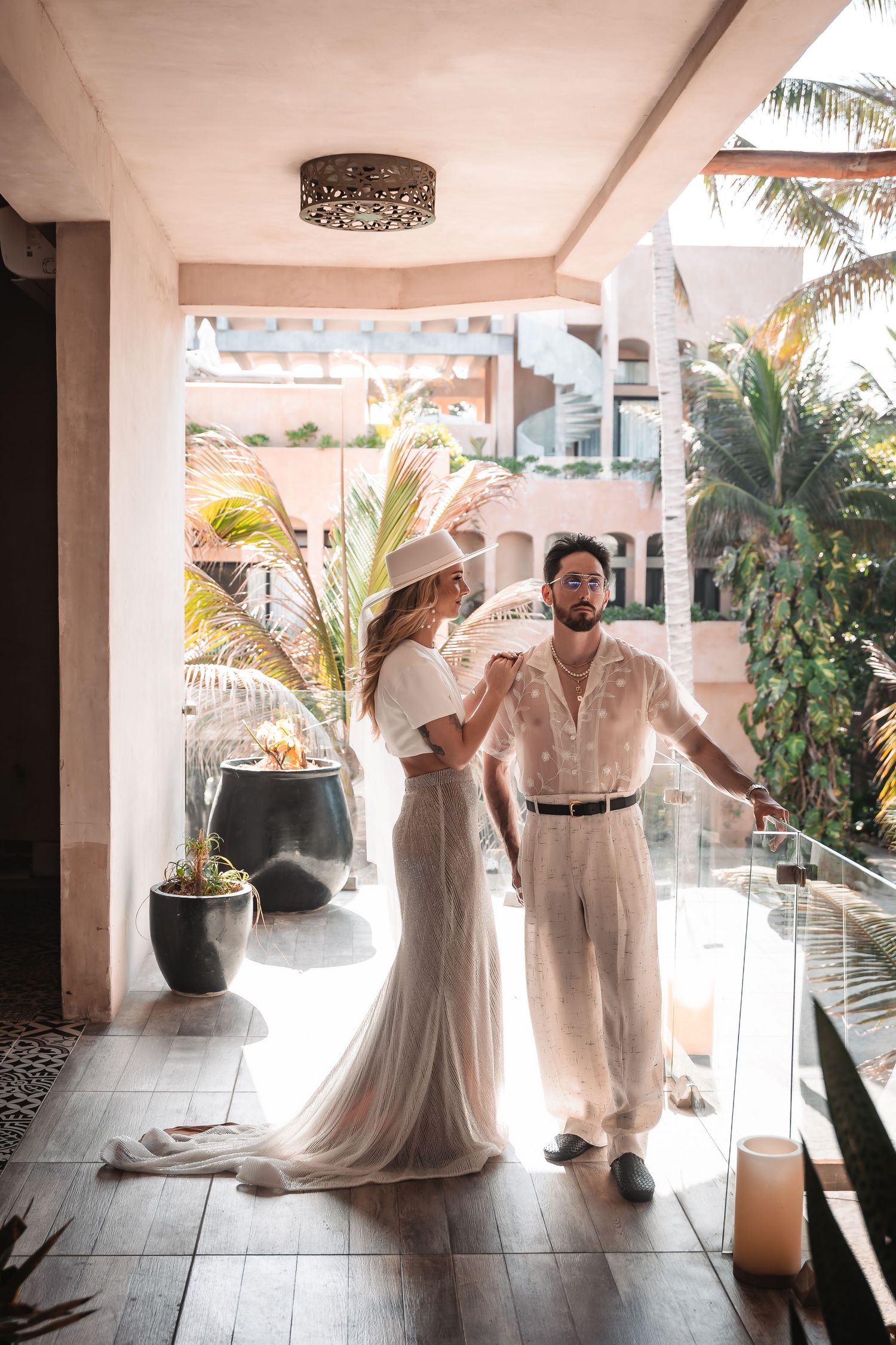 Wedding couple dances in bright tropical setting with palm trees and white decor.