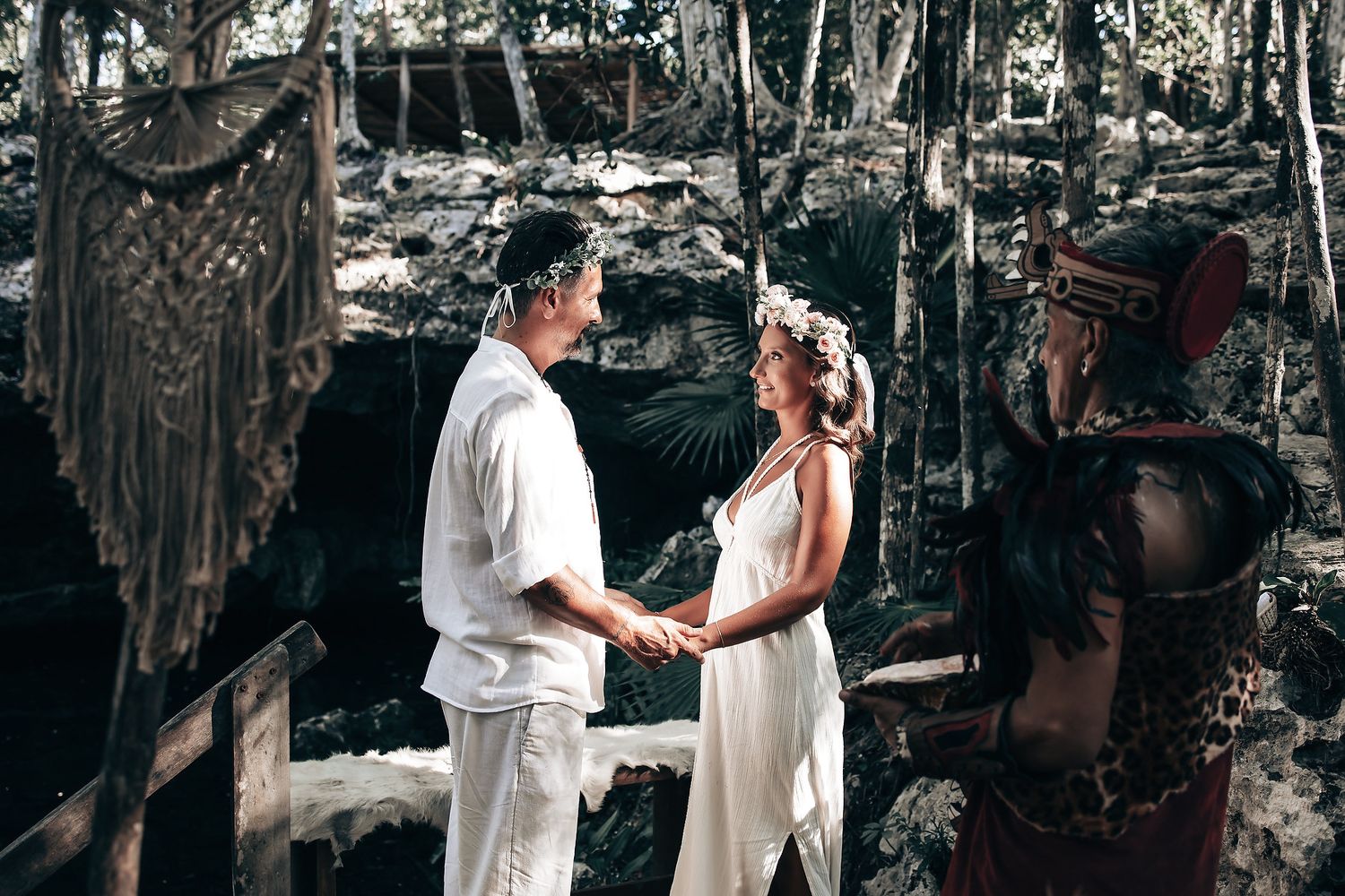 A couple standing together in a tropical forest setting, surrounded by lush vegetation.