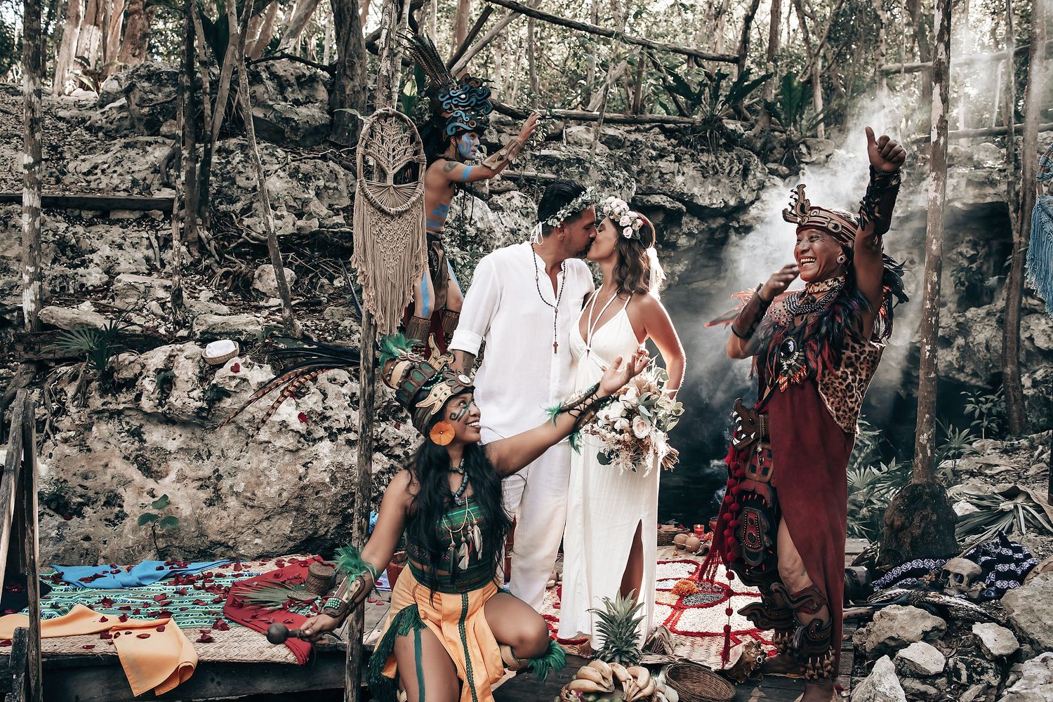 A group of people dressed in traditional tribal clothing perform a ceremony in a natural outdoor setting.