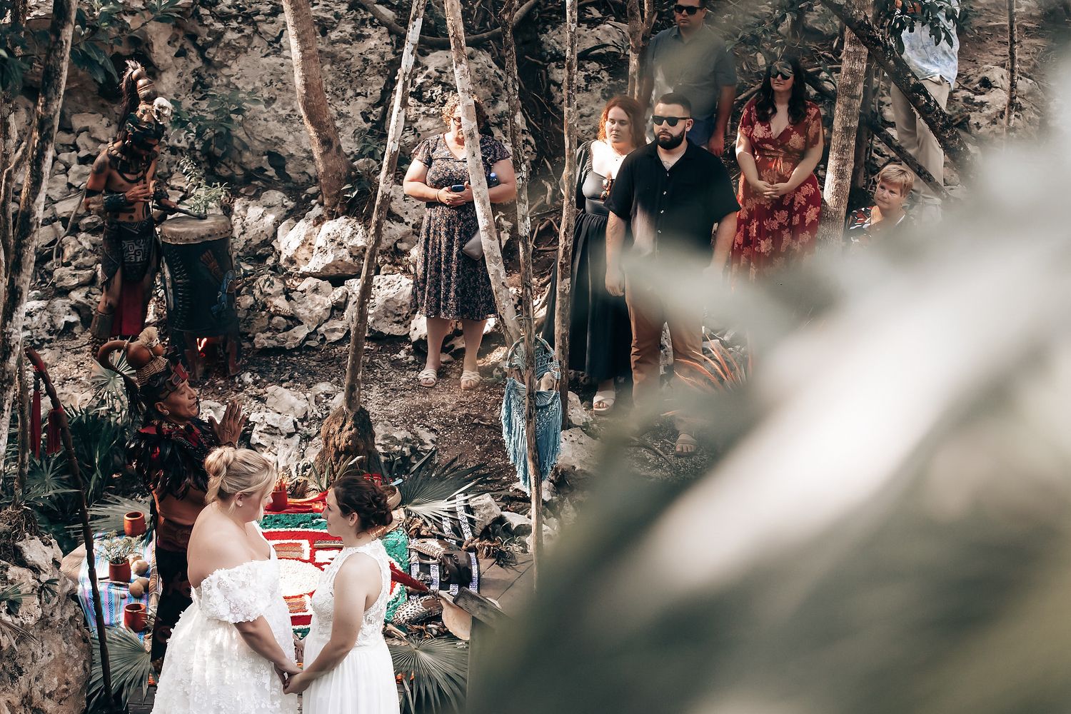 A group of people in traditional clothing standing in a jungle-like setting.