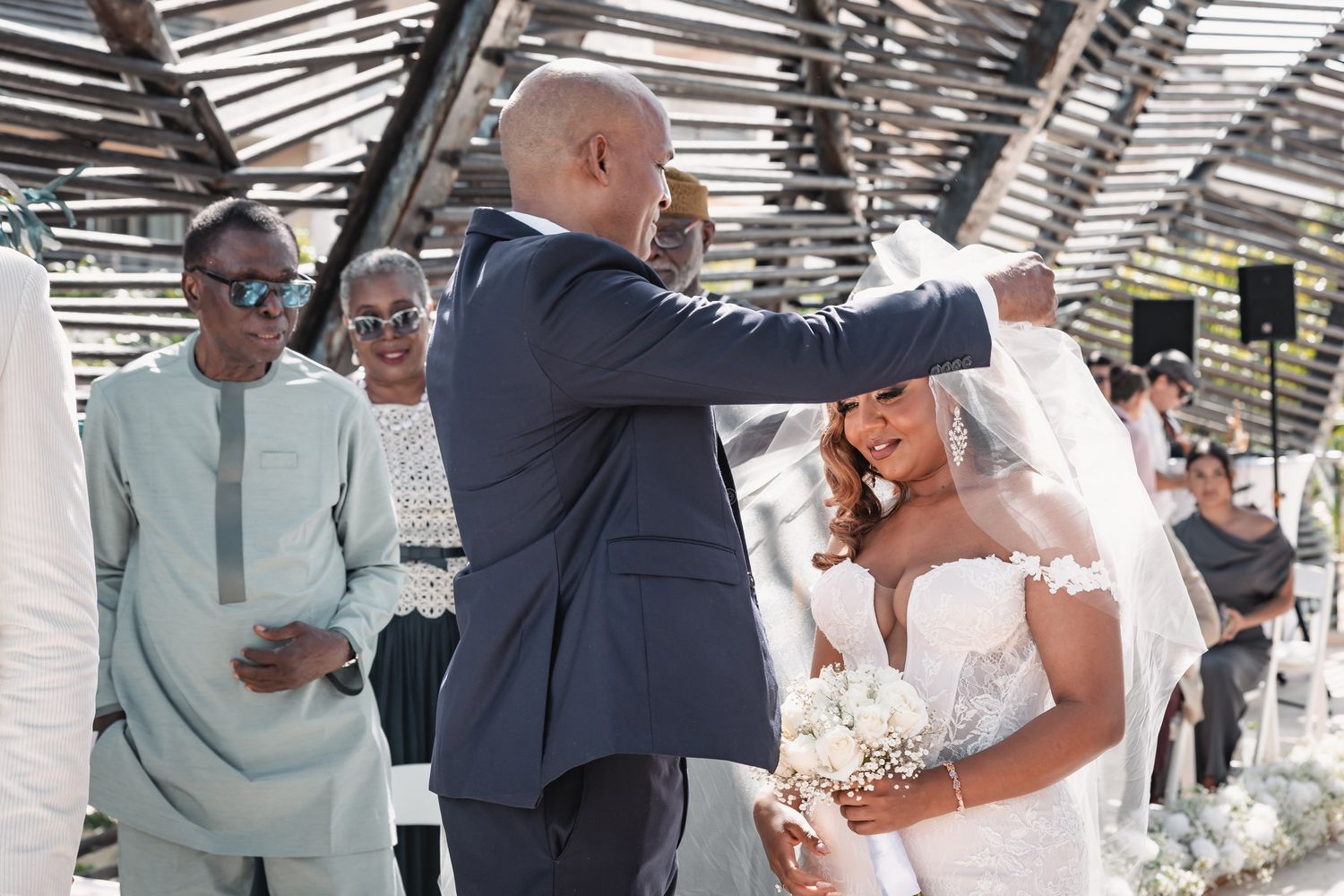 Father lifting daughters wedding veil during emotional bridal processional at outdoor wedding ceremony.
