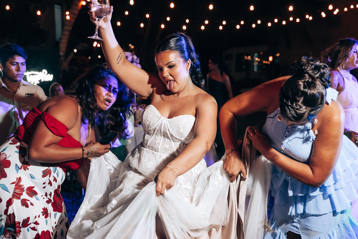 Wedding reception dance party under string lights at night.