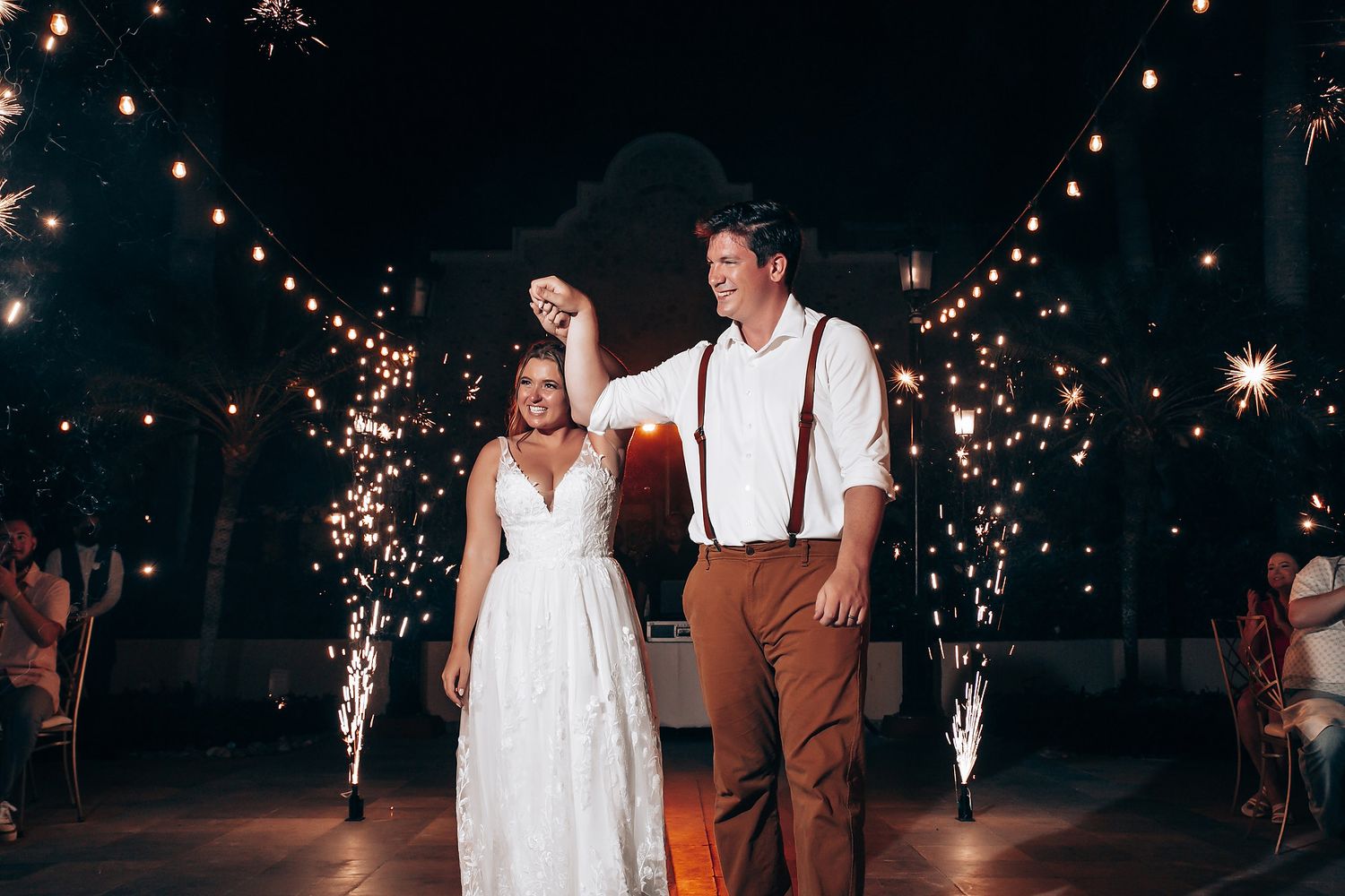 String lights illuminate an outdoor evening wedding celebration.