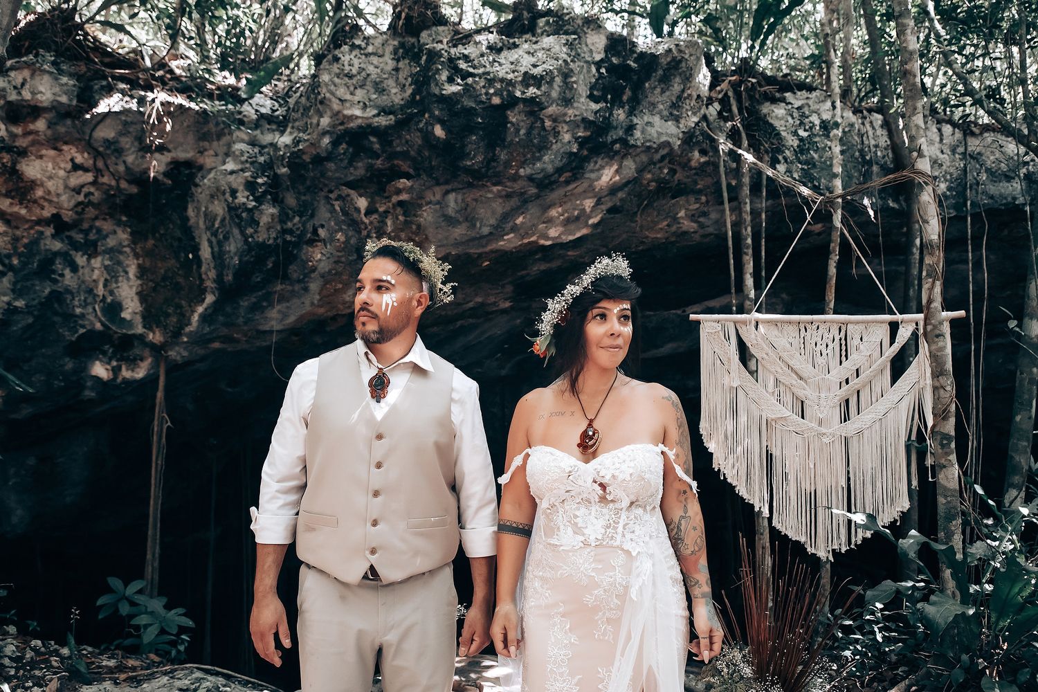 Wedding couple poses against dramatic cave backdrop with hanging decorations.