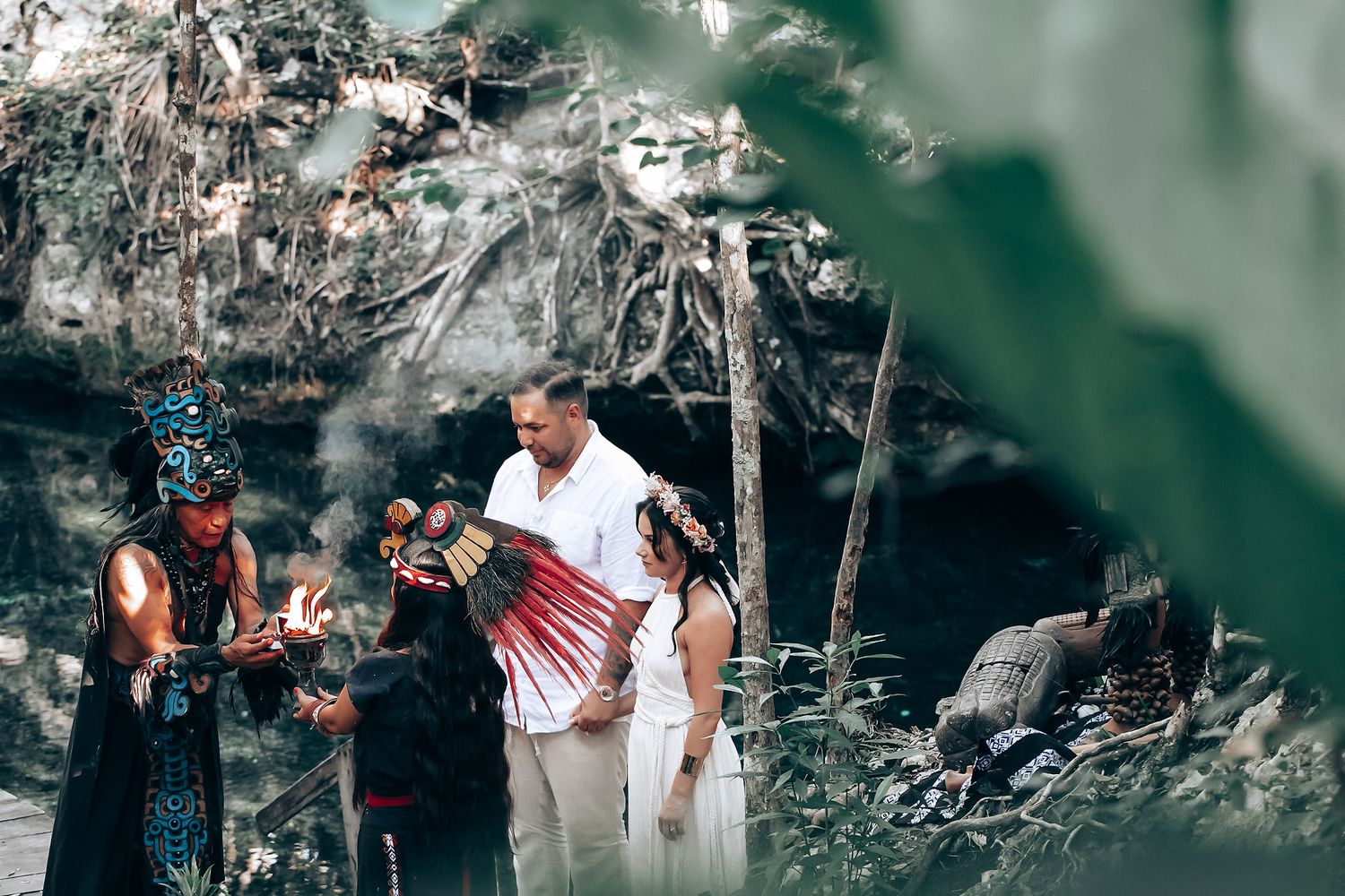 A group gathers in a natural outdoor setting with rocky terrain and greenery in the background.