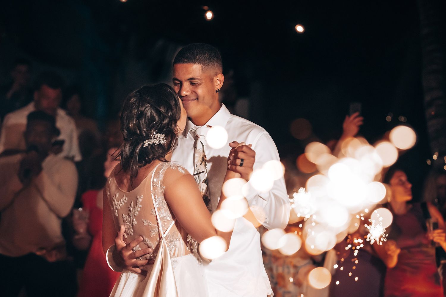Wedding reception dance floor illuminated with string lights and bokeh effects at night.