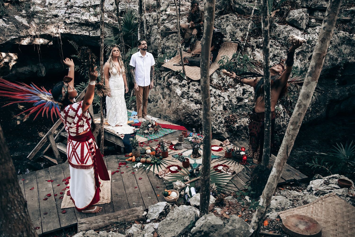 Cultural performers in traditional dress participate in a cave-based ceremony with decorative elements.