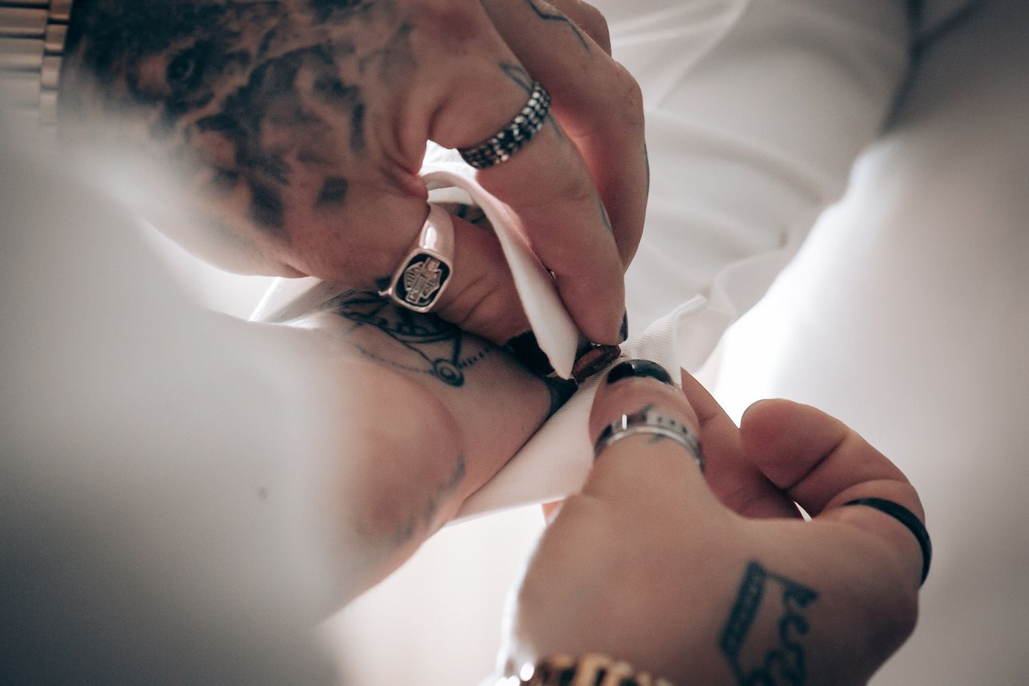 Close-up view of hands wearing multiple rings lighting a cigarette.
