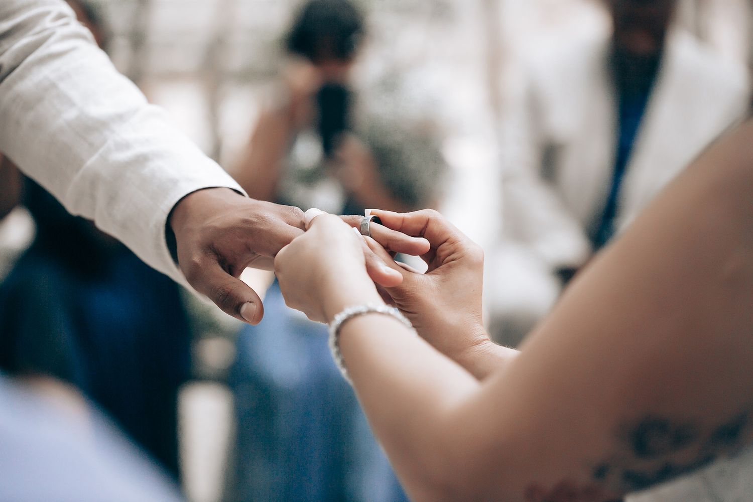 A close-up detail shot of hands exchanging wedding rings during an intimate ceremony.