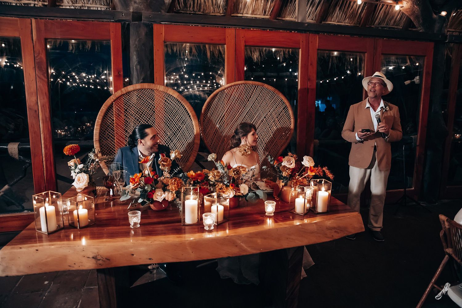Evening reception tables decorated with glowing candles and string lights creating romantic ambiance.