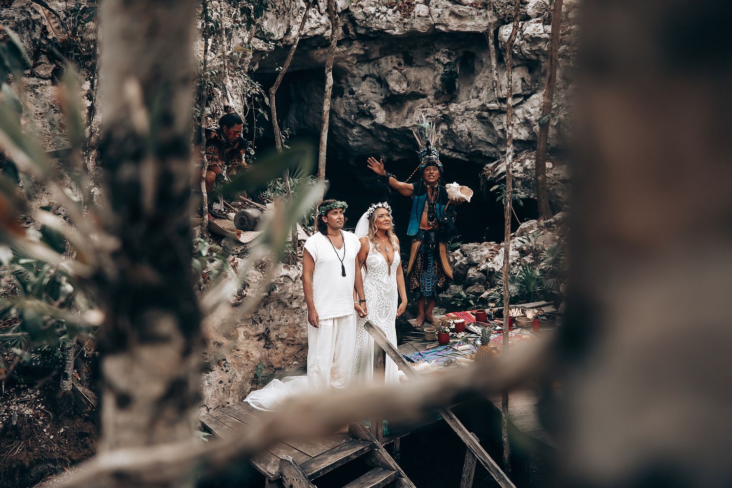 A romantic couple in white wedding attire walks through a lush garden setting during their wedding photoshoot.
