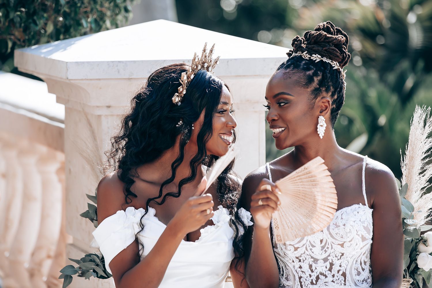 Wedding party shares joyful moments together in elegant white attire against a bright backdrop.