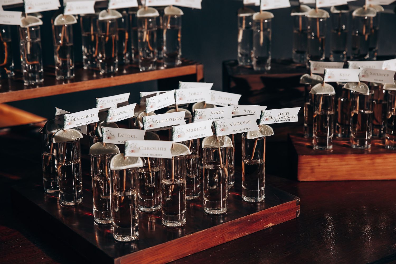 Rows of champagne flutes arranged on wooden bar surface.