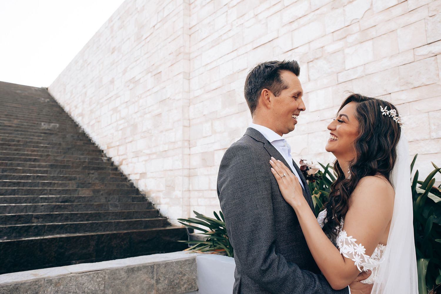 A romantic wedding couple embraces on stone steps during an outdoor photo session.