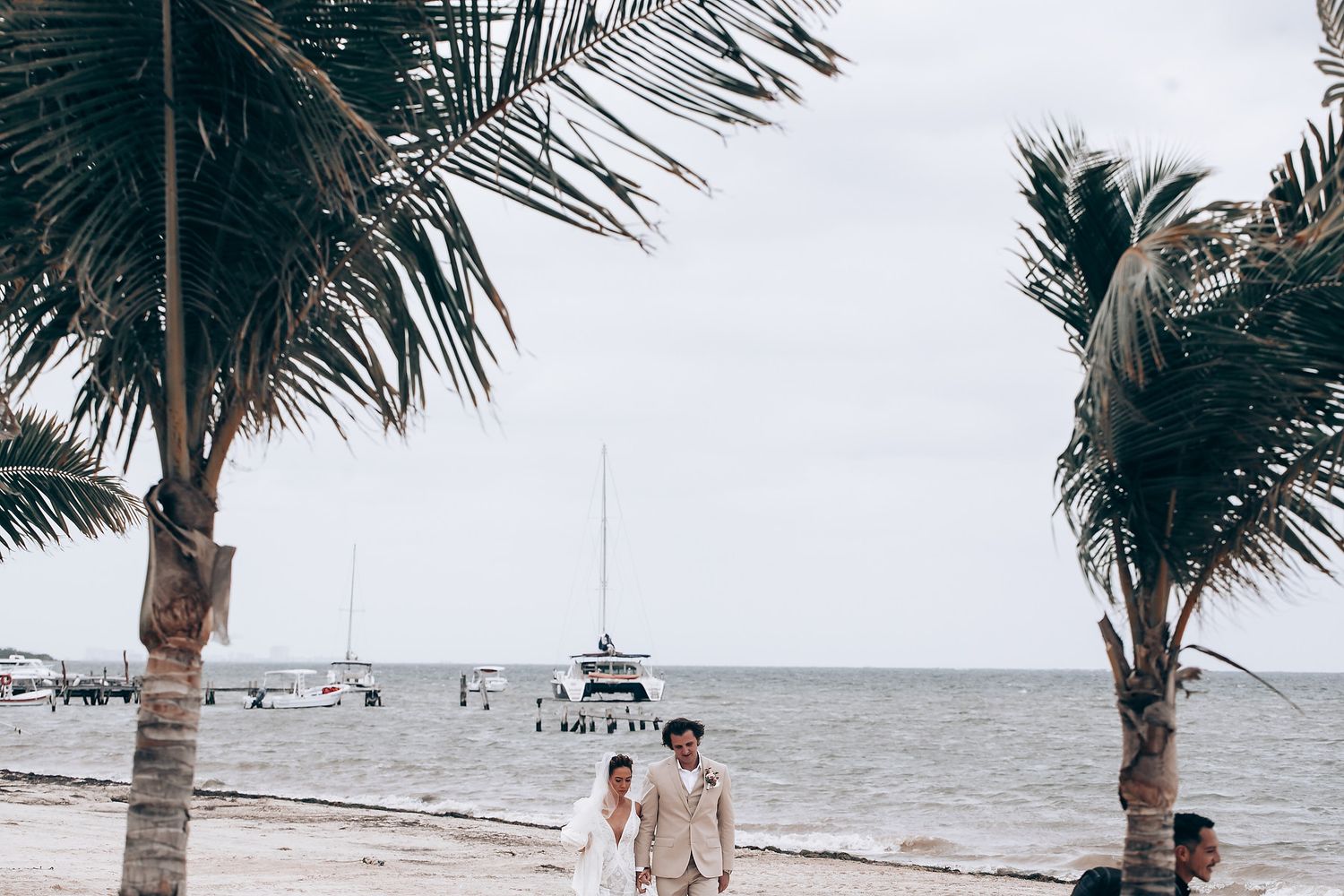 Scenic beachfront wedding setup with palm trees swaying against a cloudy coastal backdrop.