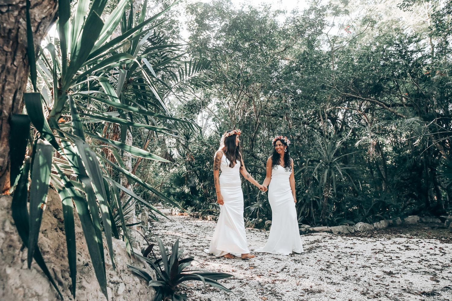 Scenic garden wedding photography session with white-dressed figures amid tropical foliage and natural light.