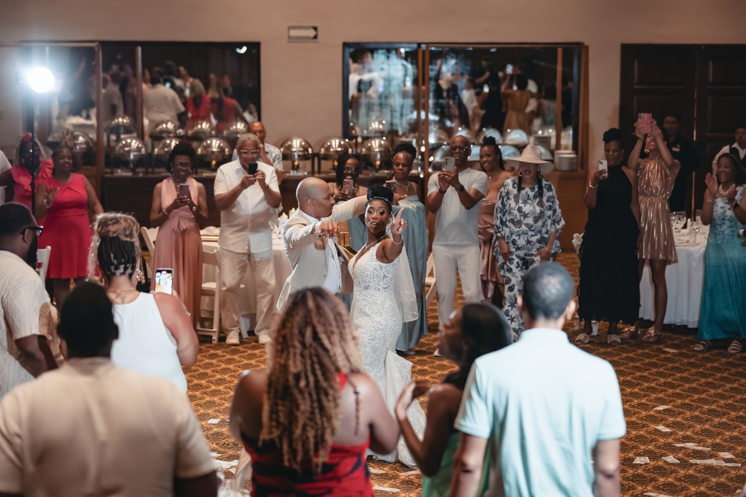 Guests in white attire celebrate and dance at an elegant indoor party or wedding reception event.