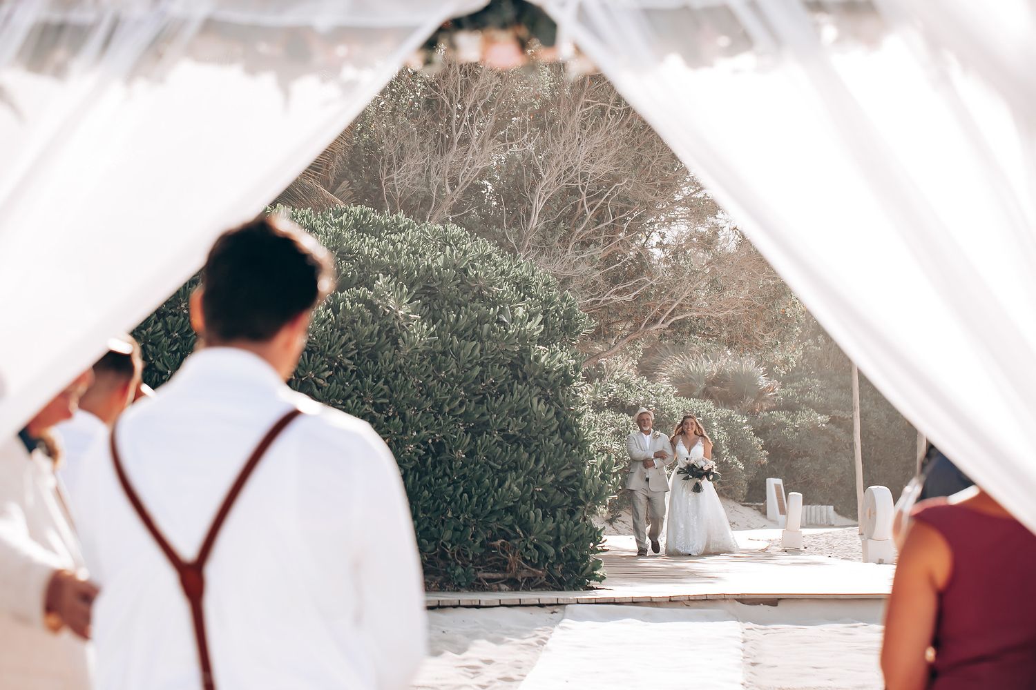 Elegant outdoor wedding reception setup with white draping and natural scenery in background.