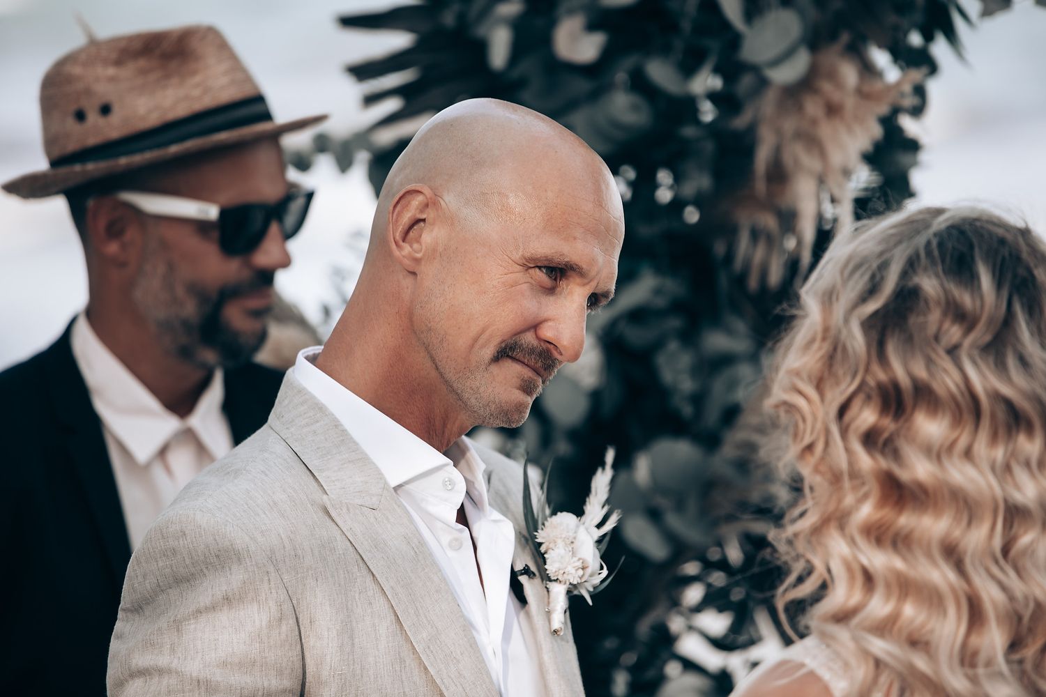 A wedding ceremony moment captured outdoors with attendees in formal attire.