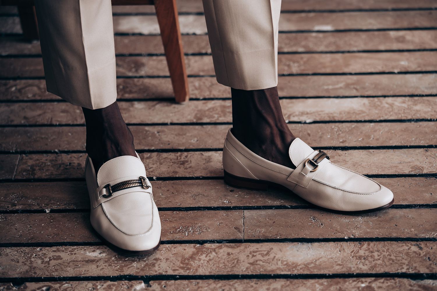 Beige leather dress shoes and loafers on wooden deck flooring.