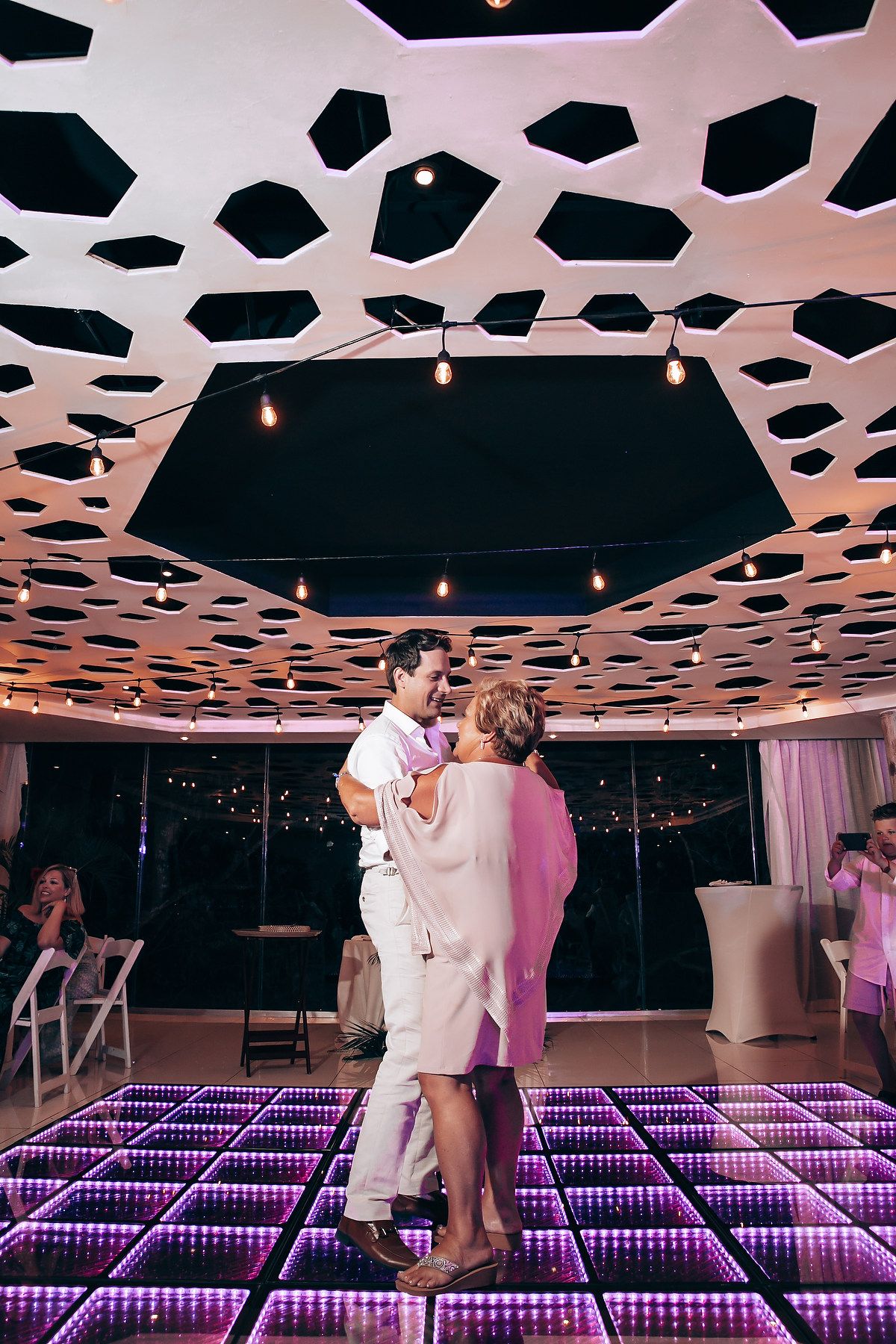 Modern wedding venue with geometric ceiling design and LED dance floor illuminated in purple.