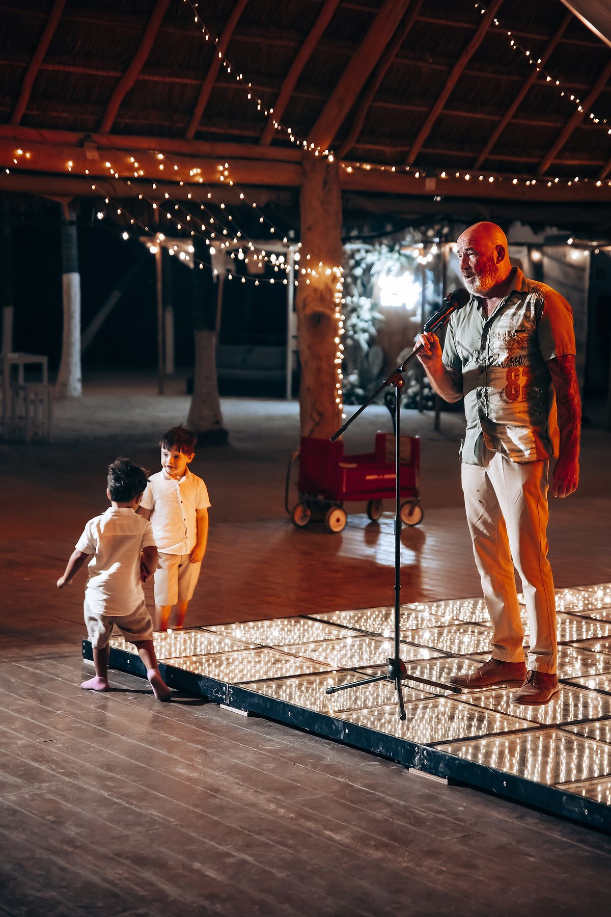 Couple setting up a romantic proposal display with glowing candles arranged on a wooden dance floor.