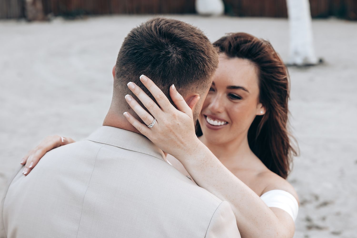 A couple embraces and laughs together on a beach during a romantic photoshoot.