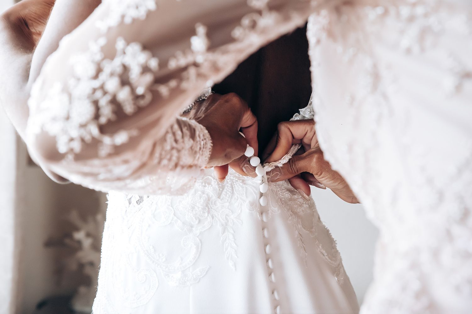 Close-up details of intricate white lace wedding dress fabric.