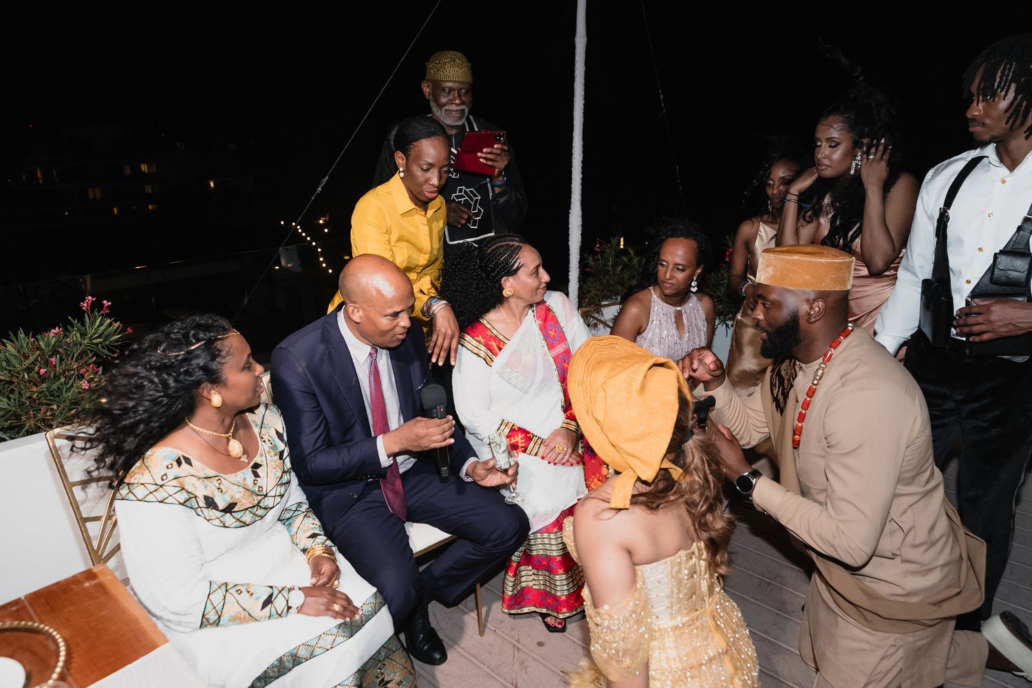 Wedding guests mingling and celebrating at lively outdoor nighttime reception party.