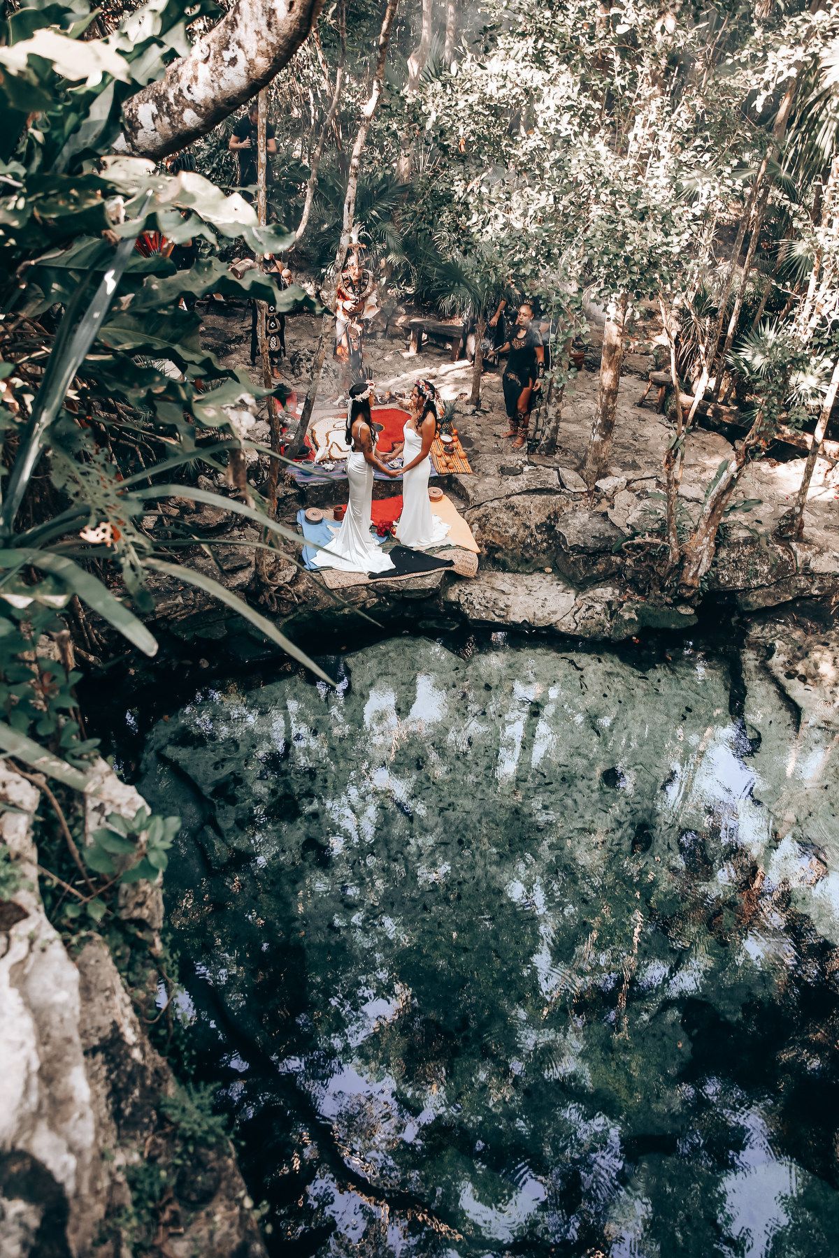 Swimmers gather around a scenic cenote surrounded by lush jungle vegetation in Mexico.