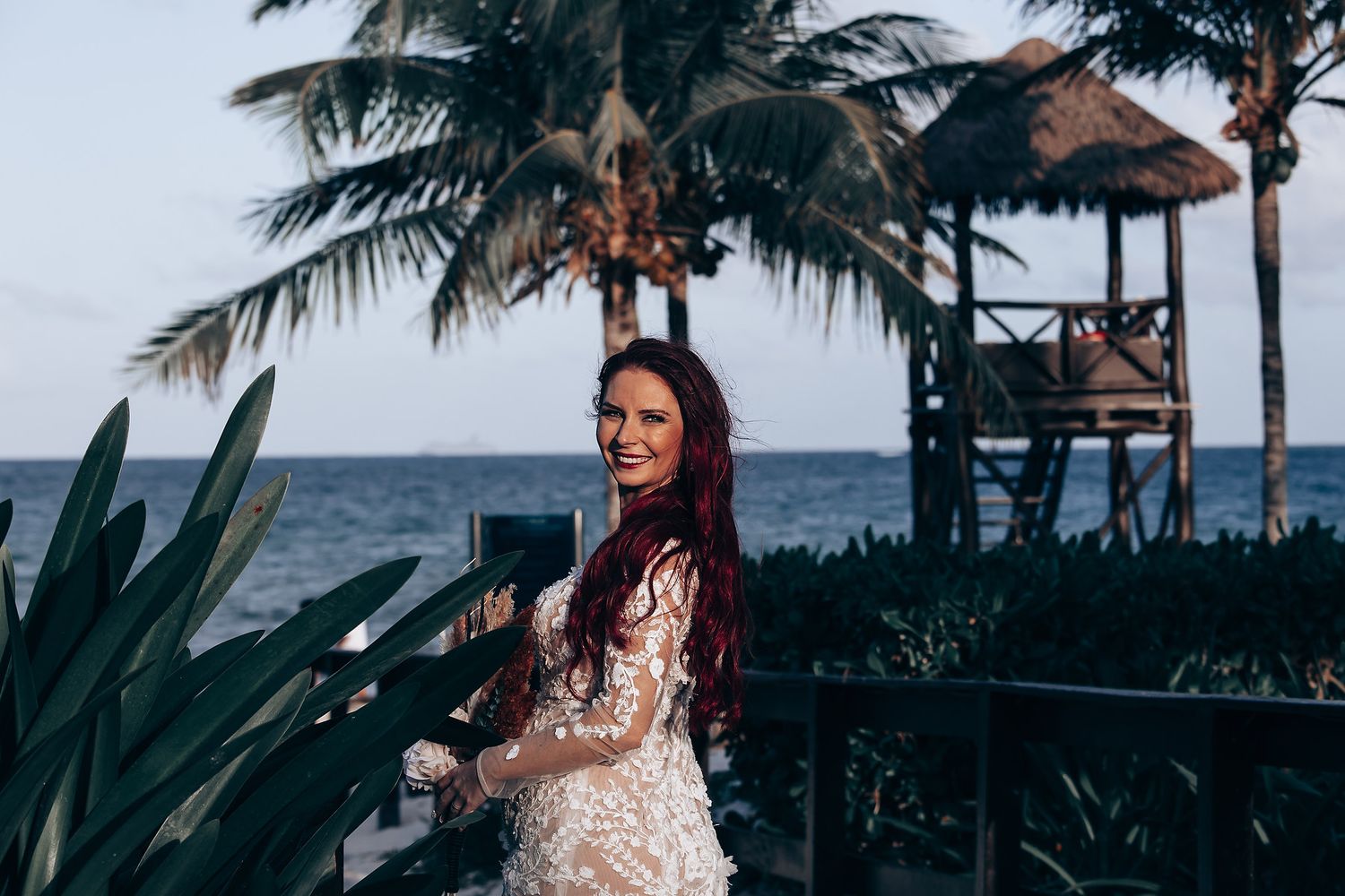 Tropical beachfront wedding venue with palm trees and ocean views at sunset.